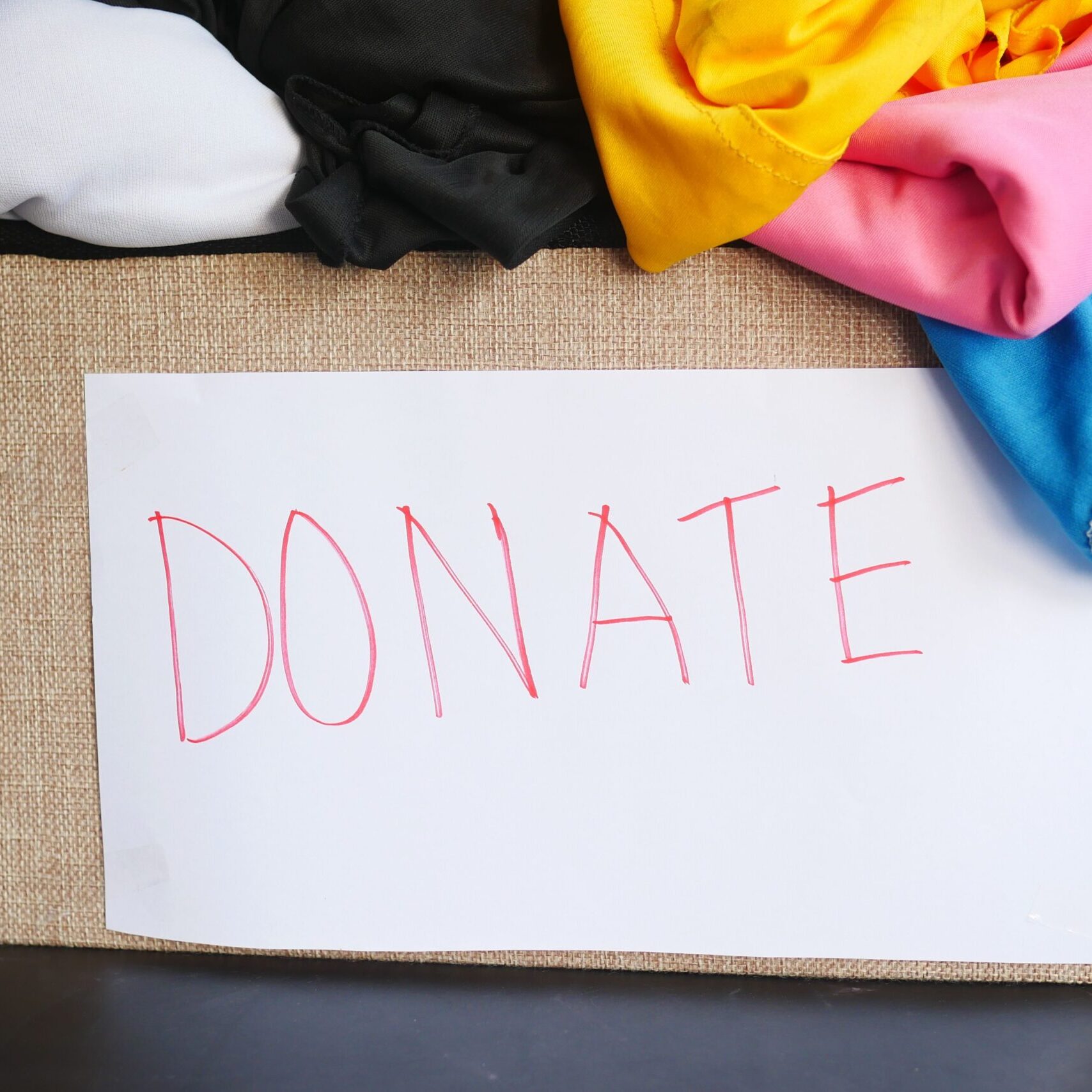 A donation box filled with colorful clothing, symbolizing charity and community support.